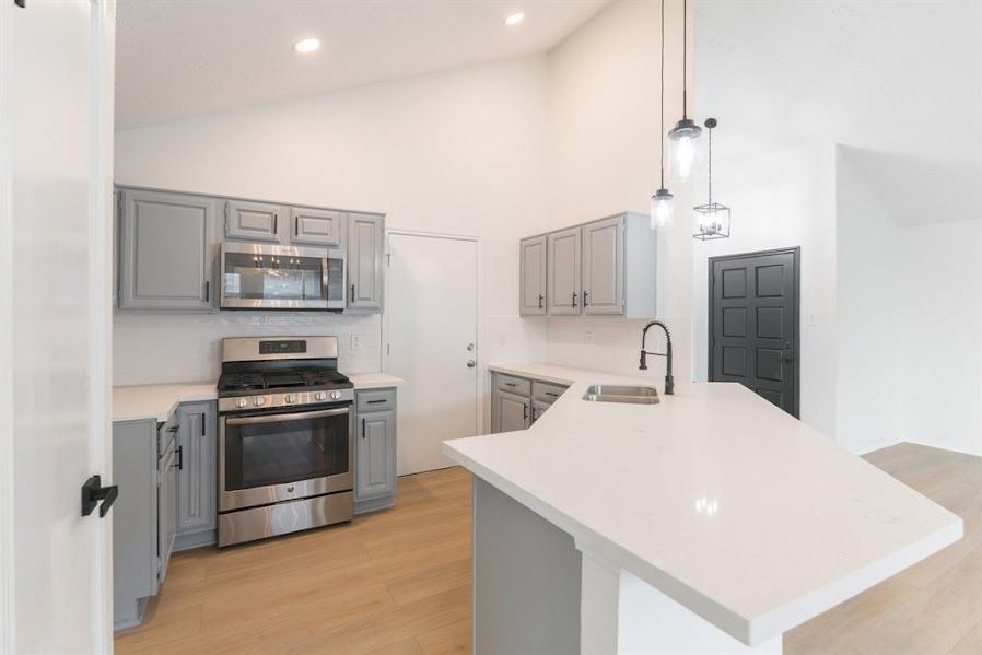 A kitchen with stainless steel appliances and gray cabinets