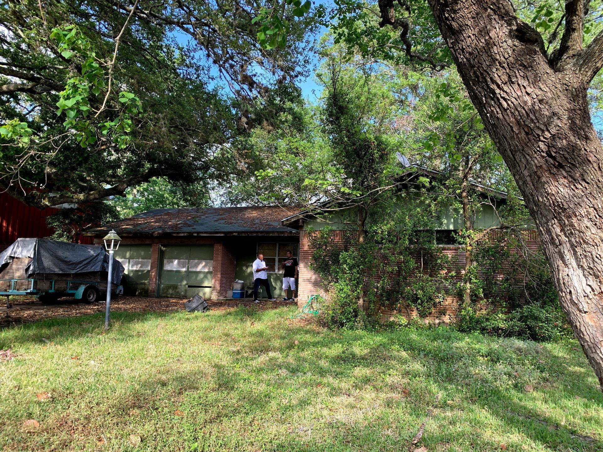 A man is standing in front of a house surrounded by trees.