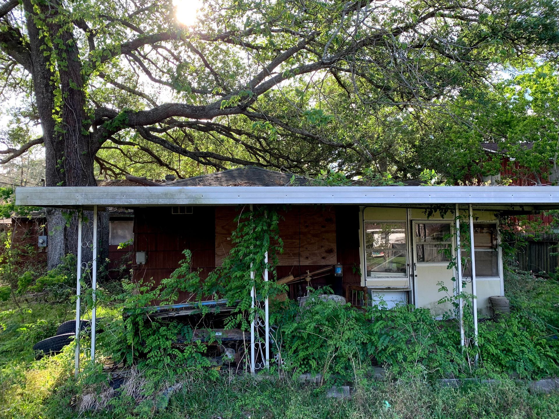 An old abandoned house with a tree in the background.