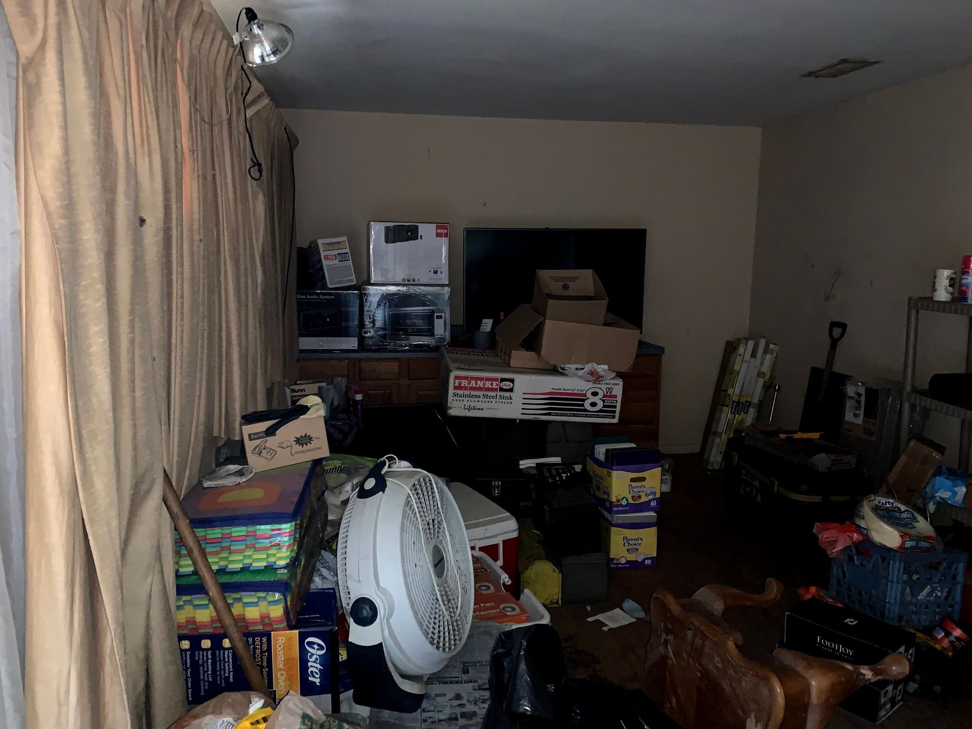 A living room filled with lots of boxes and a fan