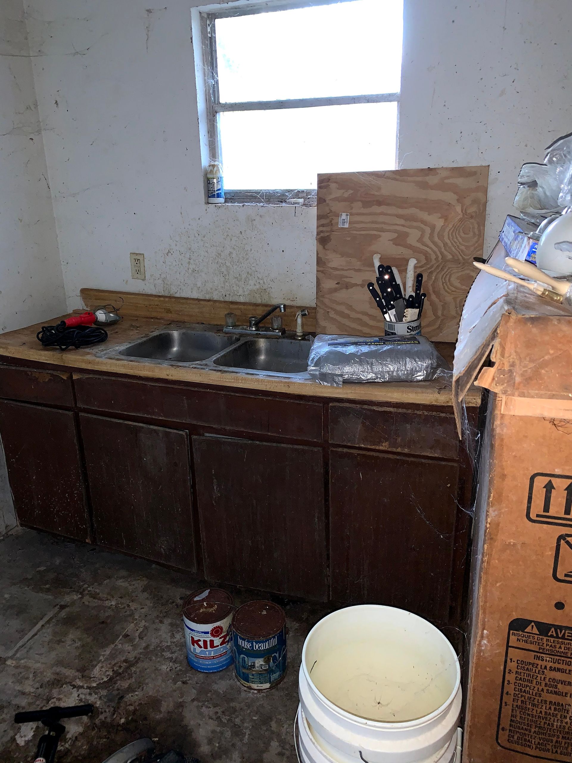 A kitchen with a sink and buckets of paint