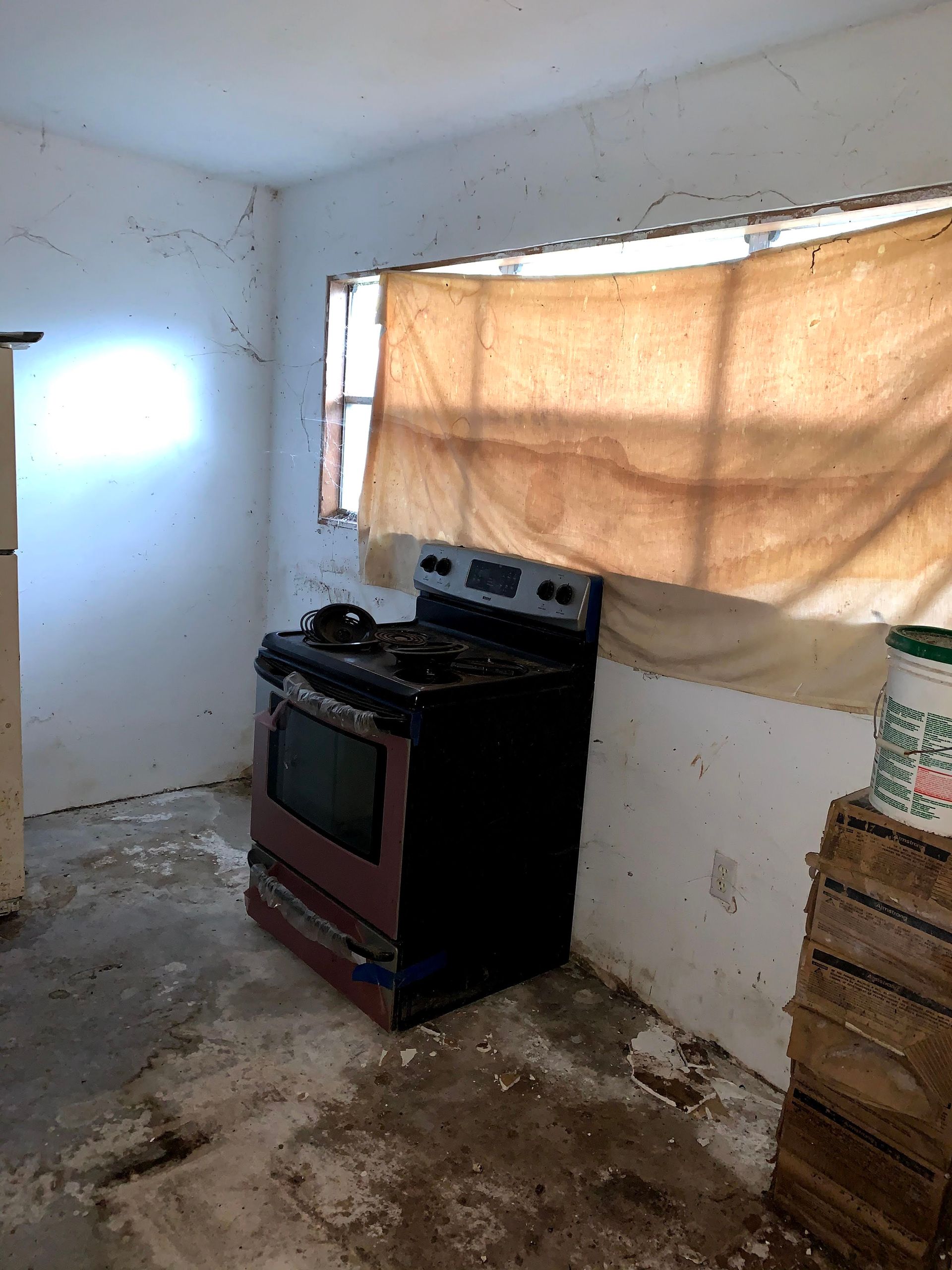 An empty kitchen with a stove and a window.