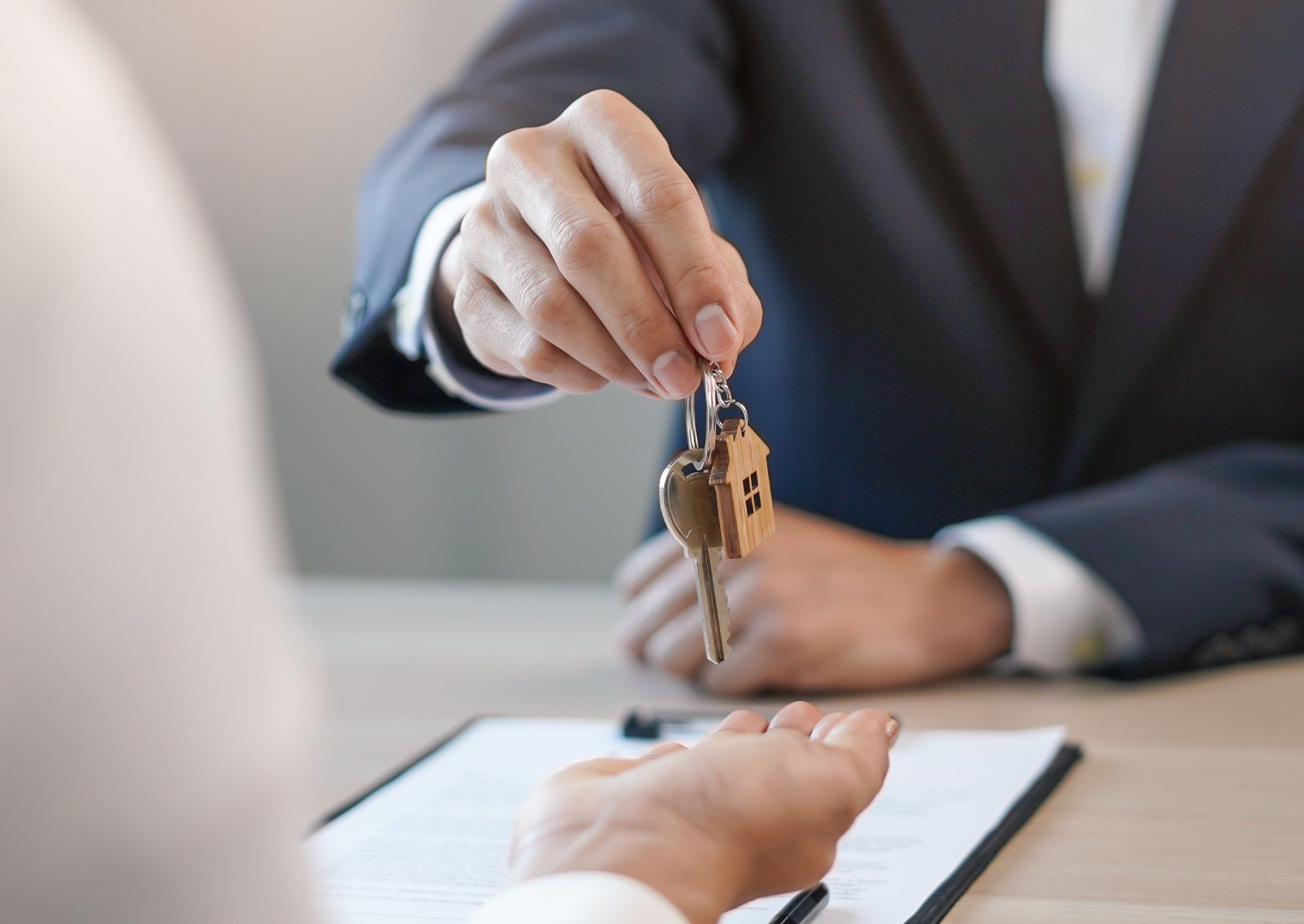 A man in a suit is giving a woman a set of keys.