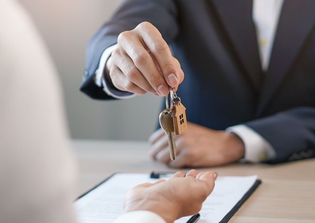 A man in a suit is giving a woman a set of keys.