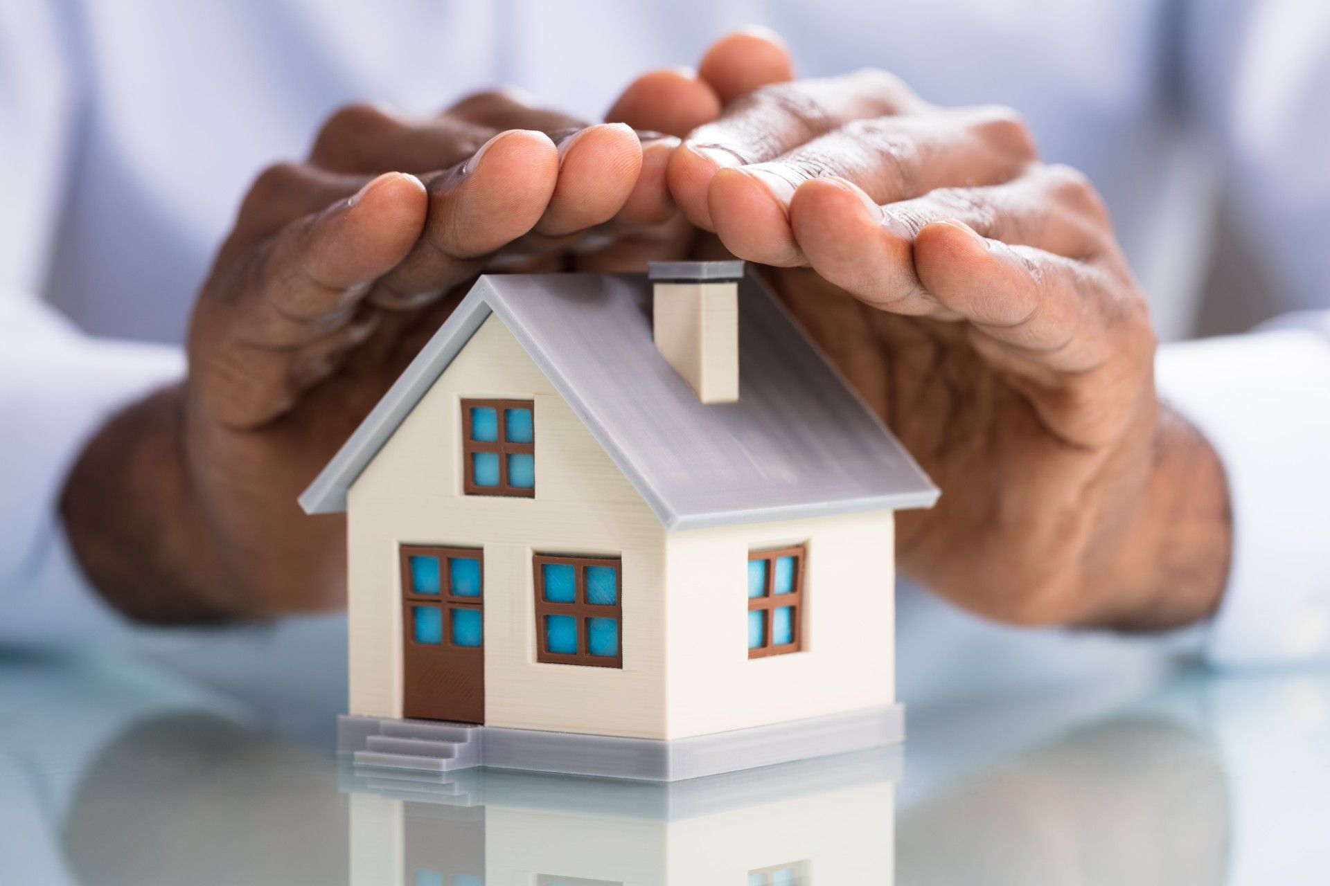 A person is holding a small house in their hands.