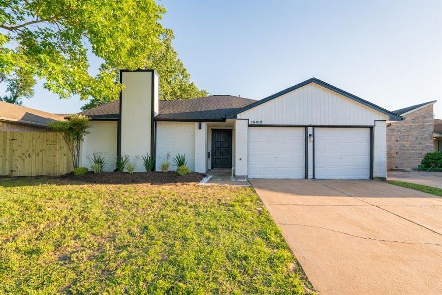A white house with two garage doors is for sale