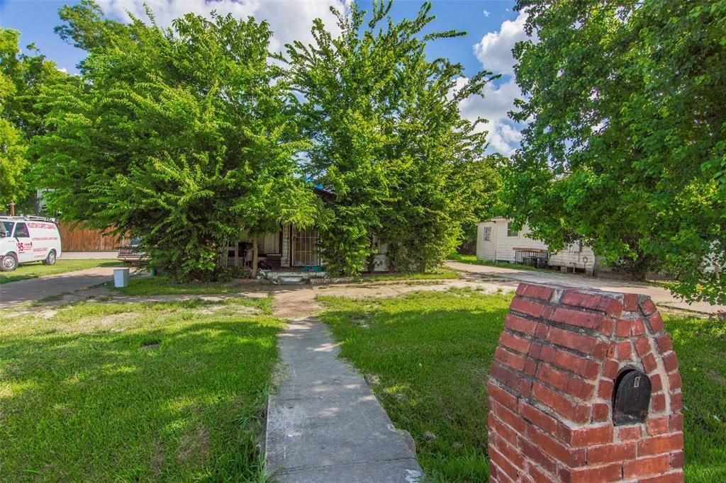 A brick mailbox is sitting in the grass in front of a house.