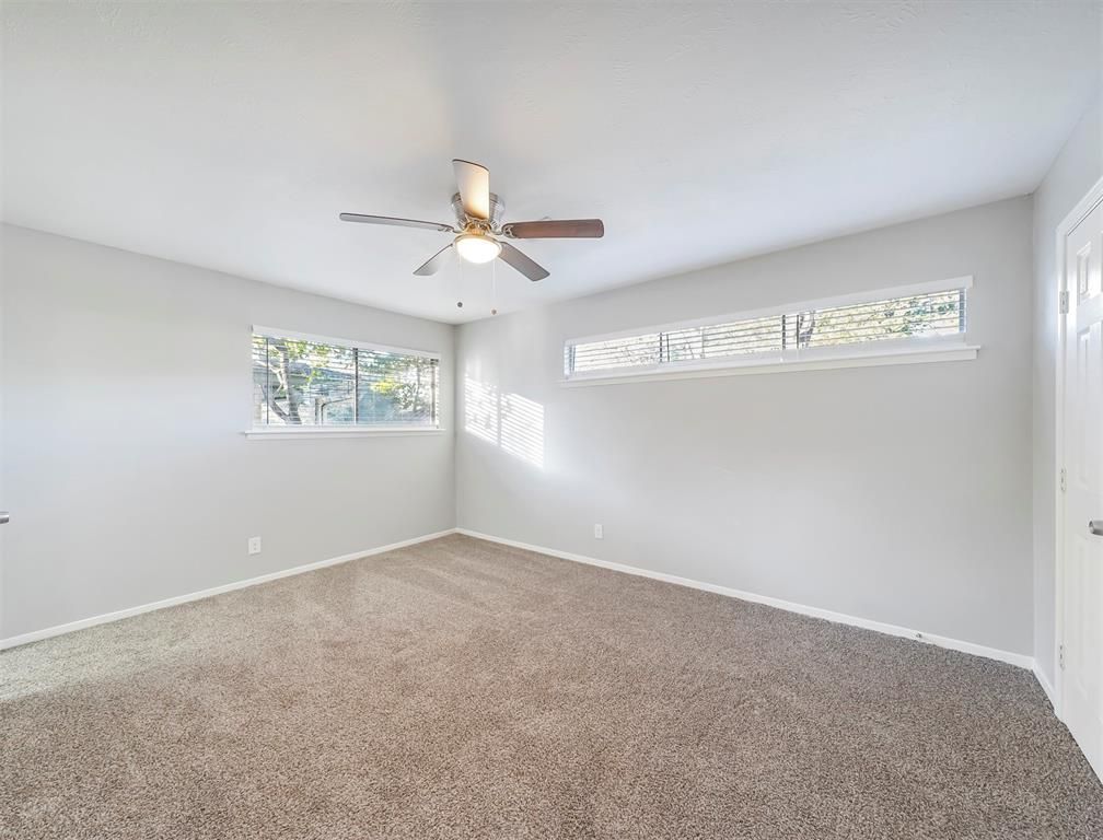 An empty bedroom with a ceiling fan and a window.