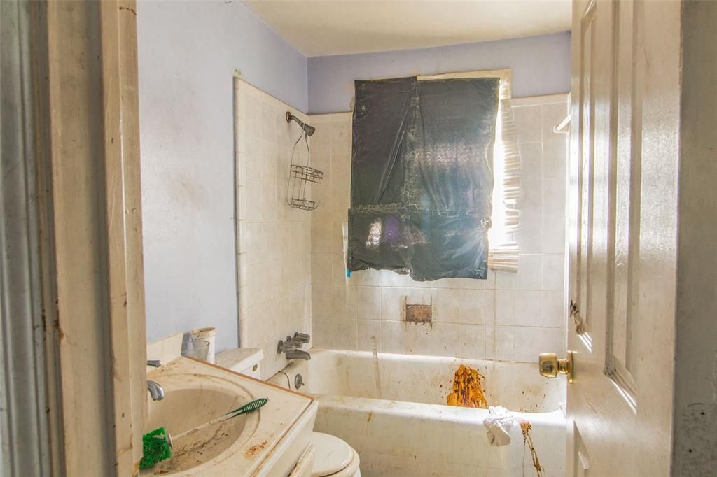 A bathroom with a sink , toilet , bathtub and window.