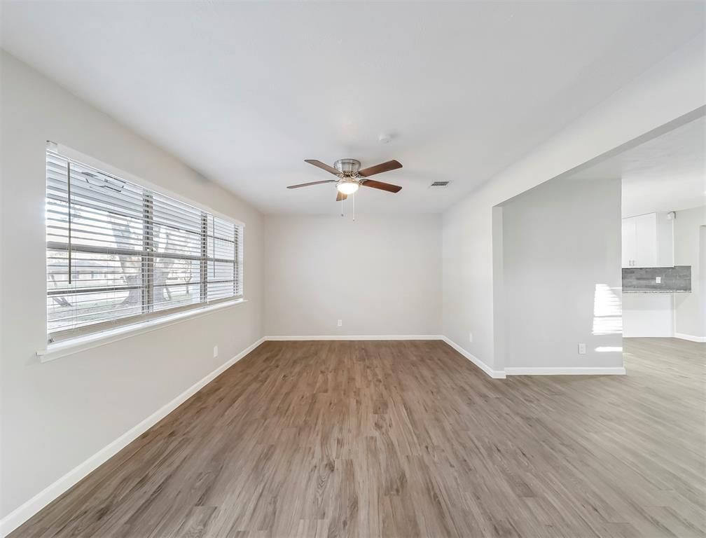 An empty living room with hardwood floors and a ceiling fan.