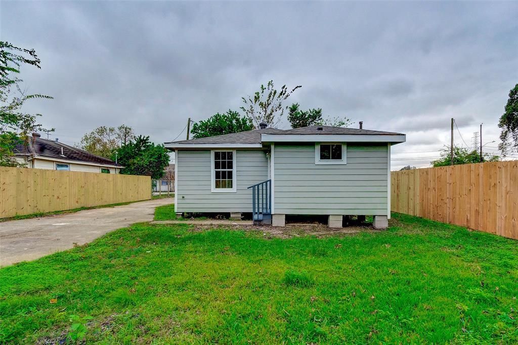 A small white house with a wooden fence in front of it.