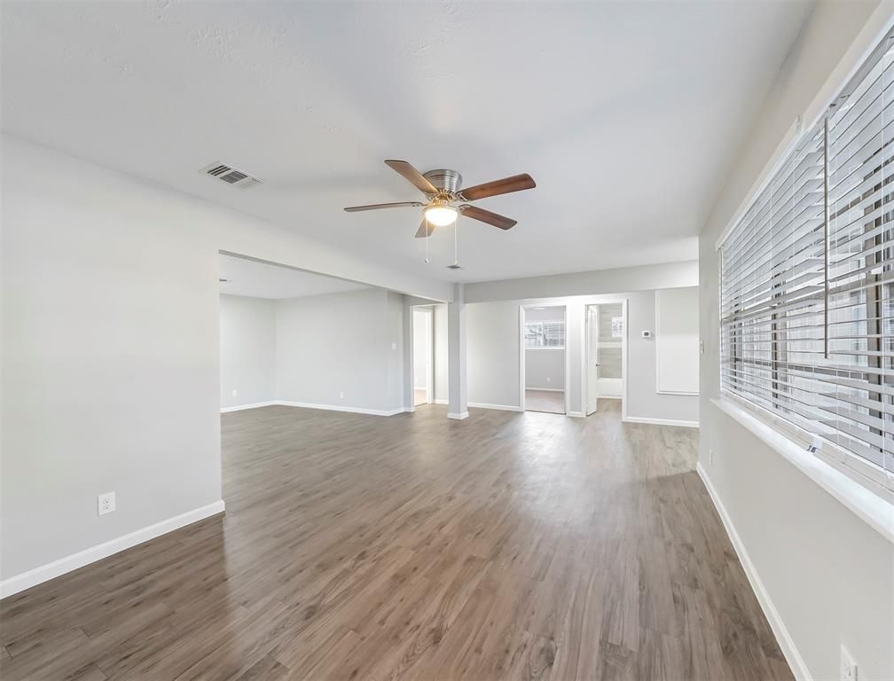 An empty living room with hardwood floors and a ceiling fan.
