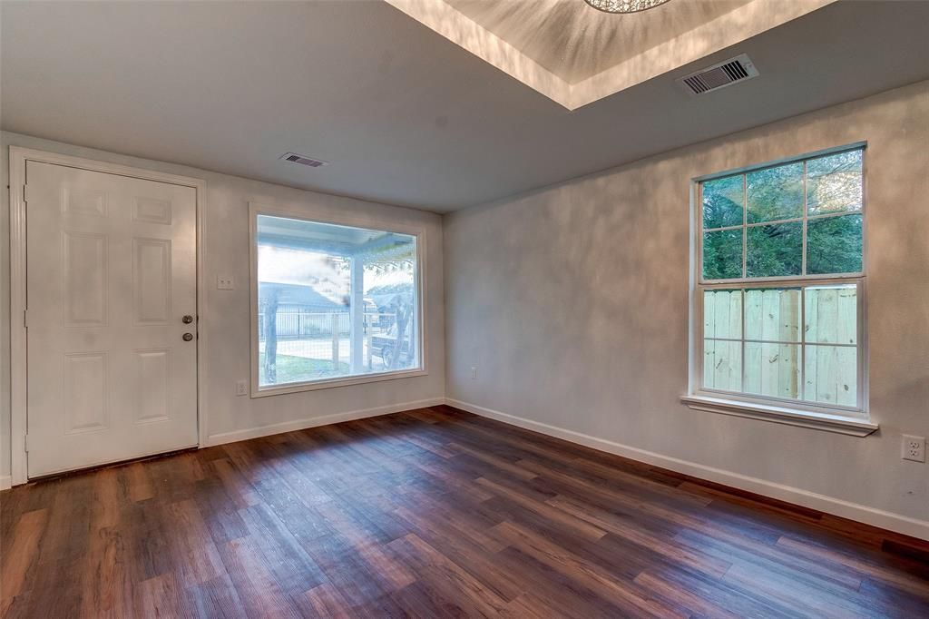 An empty living room with hardwood floors and a chandelier.