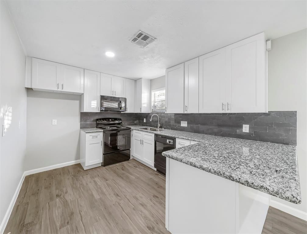 A kitchen with white cabinets , granite counter tops , and stainless steel appliances.