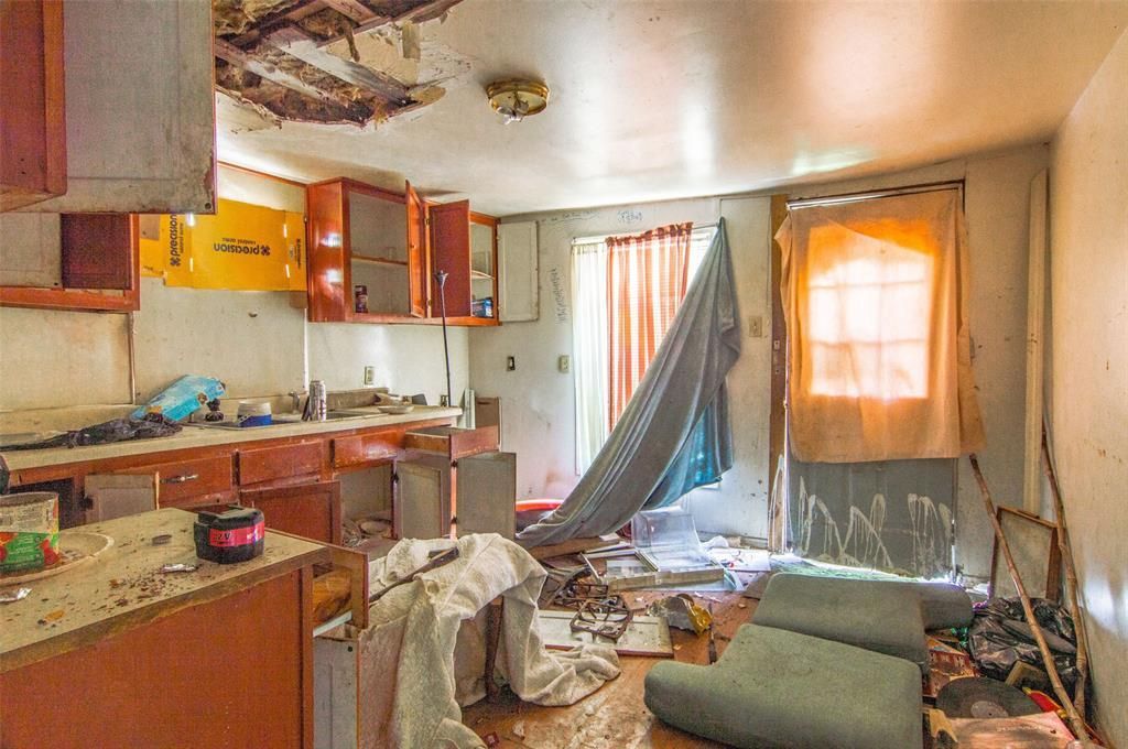 A kitchen in an abandoned house with a tarp hanging from the ceiling.