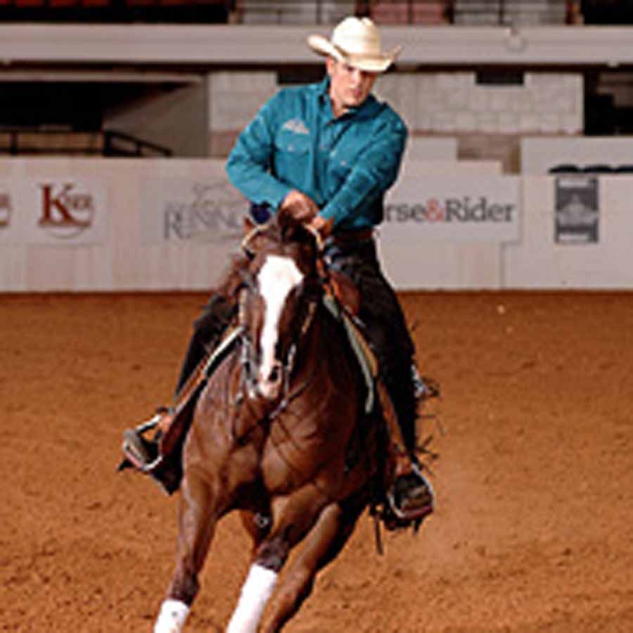 Cowboy in a white hat riding a galloping brown horse in an indoor arena