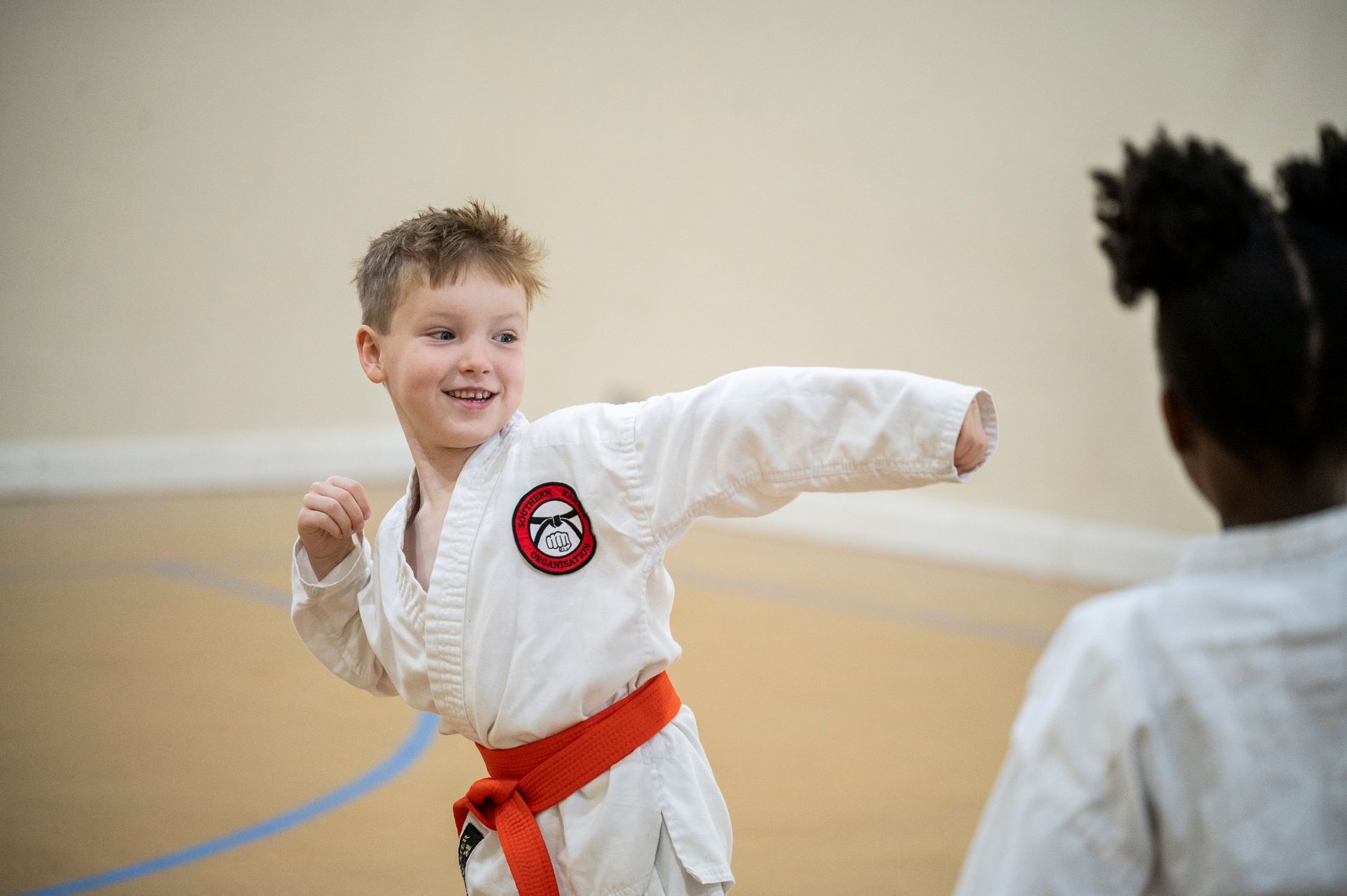 A young boy is practicing karate with a woman in a gym.