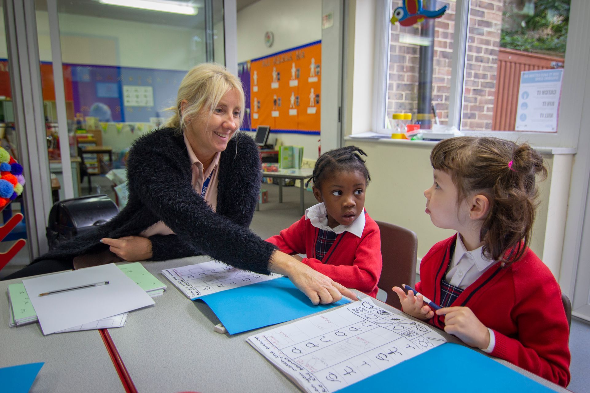 A woman is teaching two young girls in a classroom.