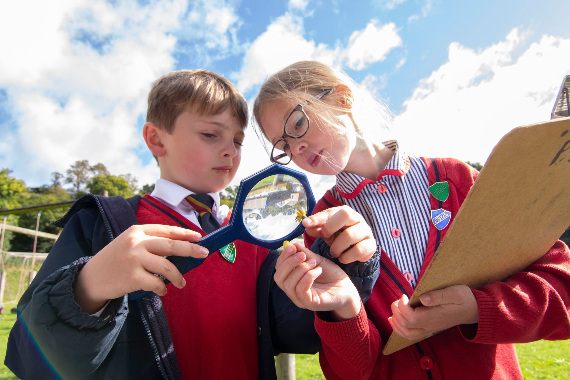 A boy and a girl are looking through a magnifying glass.