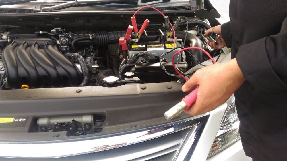 A Person Is Charging A Car Battery With Jumper Cables — Tamworth Muffler Man In Tamworth, NSW