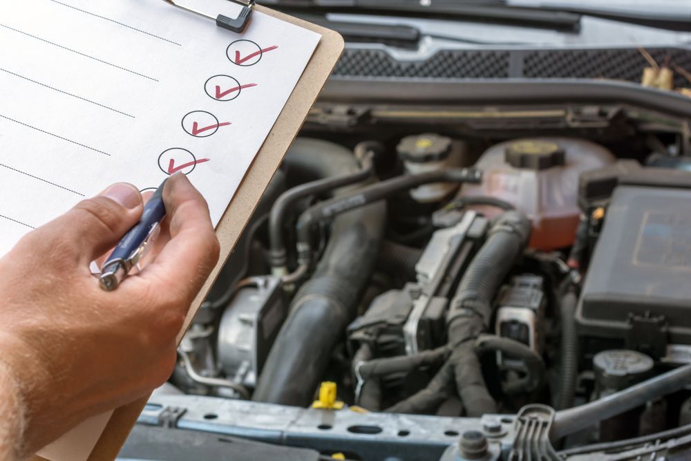 A Person Is Writing On A Clipboard In Front Of A Car Engine— Tamworth Muffler Man In Tamworth, NSW