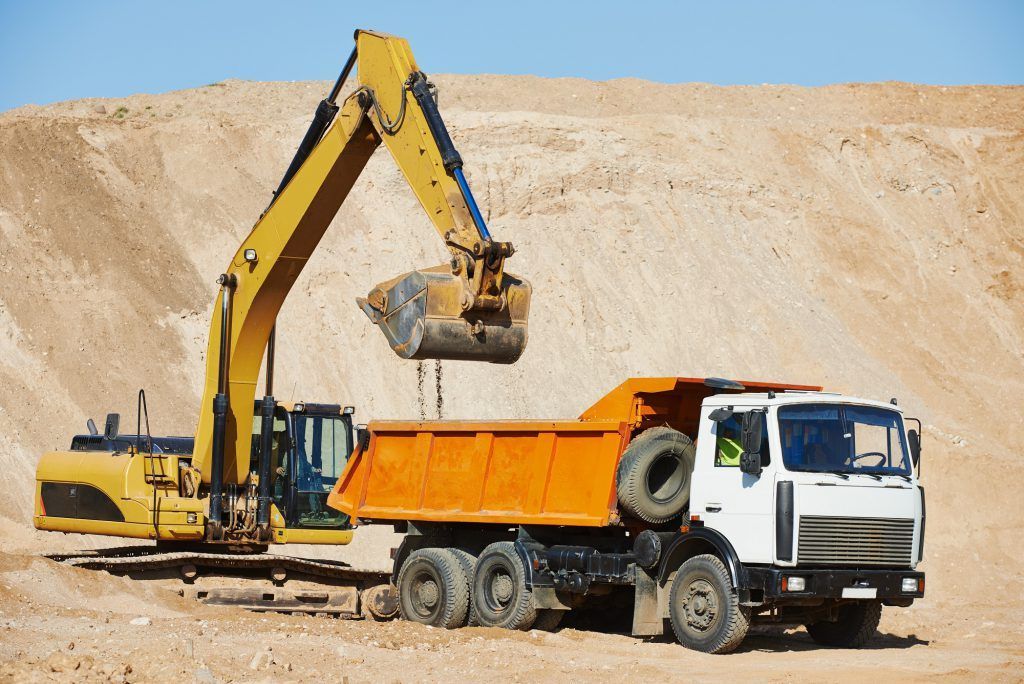 A Dump Truck Is Being Loaded With Dirt By An Excavator — Tamworth Muffler Man In Tamworth, NSW