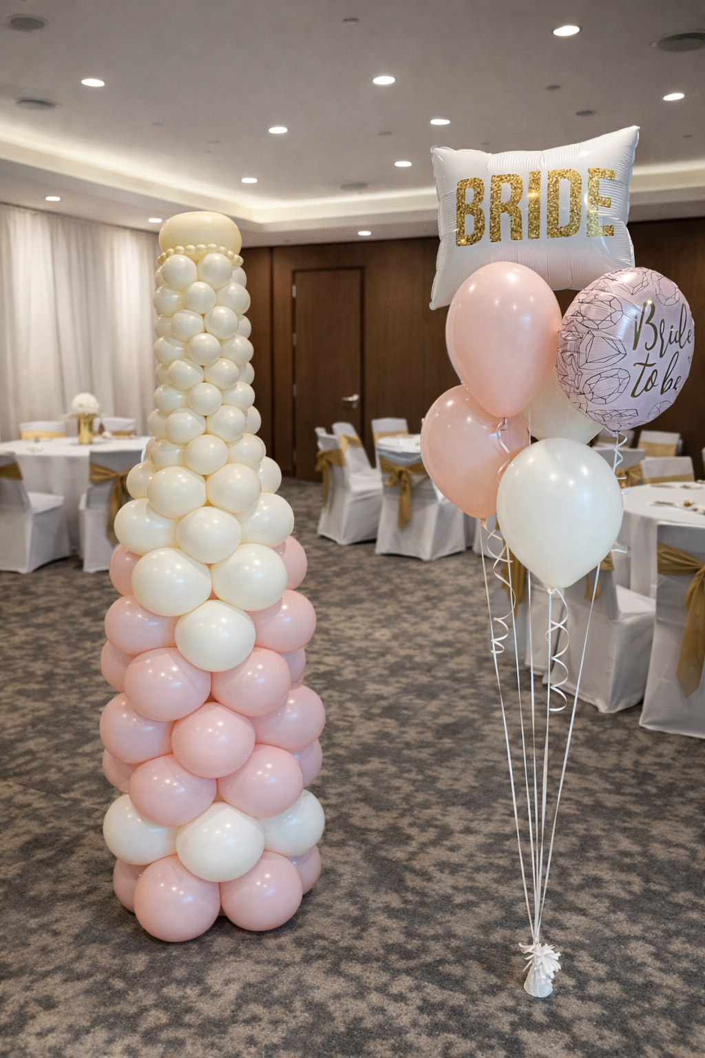 Pastel balloon towers and a “BRIDE” balloon sign in a decorated banquet room
