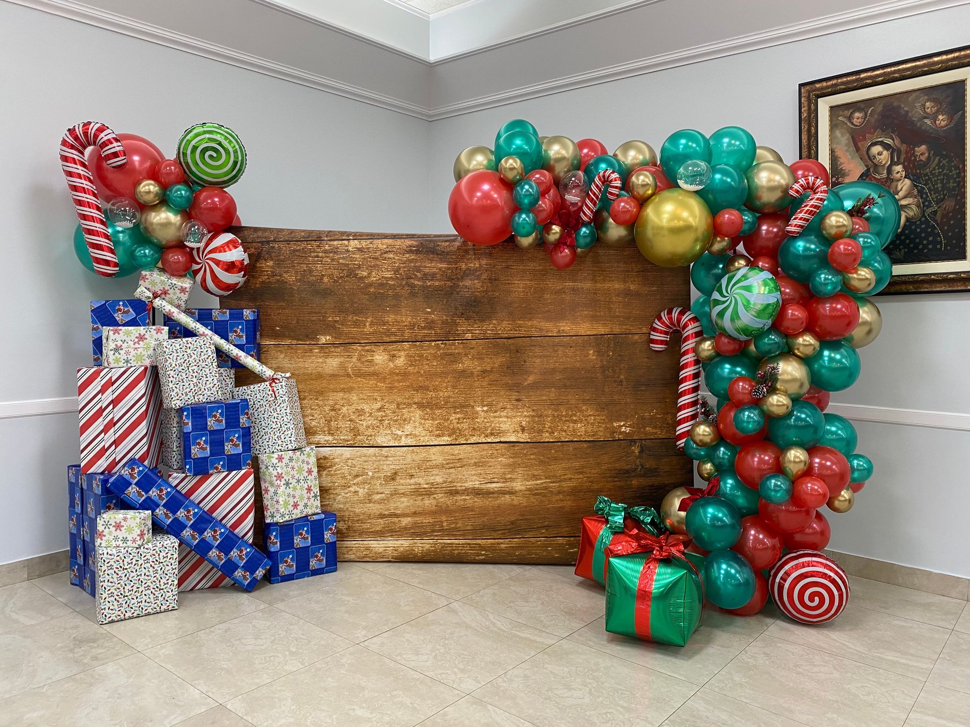 Balloon arch, wrapped gifts, and a wooden backdrop in a decorated party room