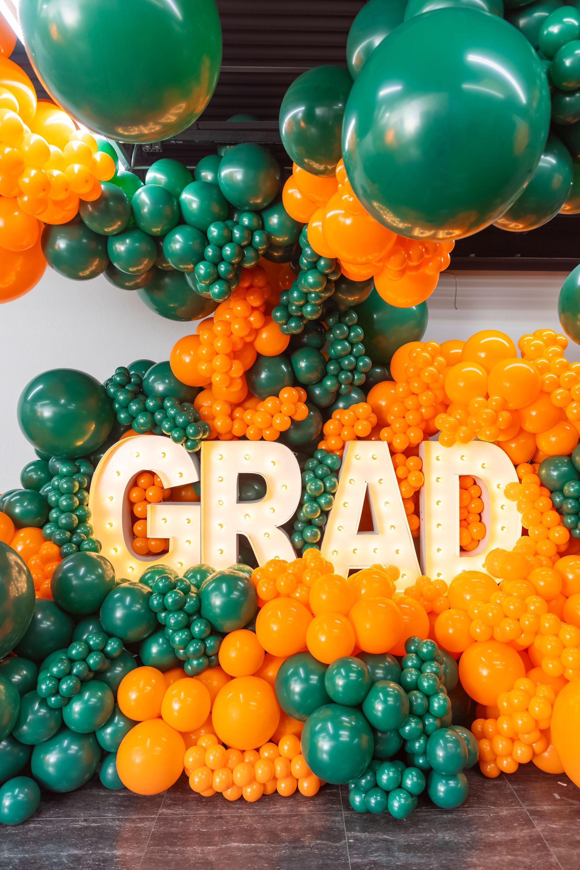 Green and orange balloon display with “GRAD” letters for a graduation celebration
