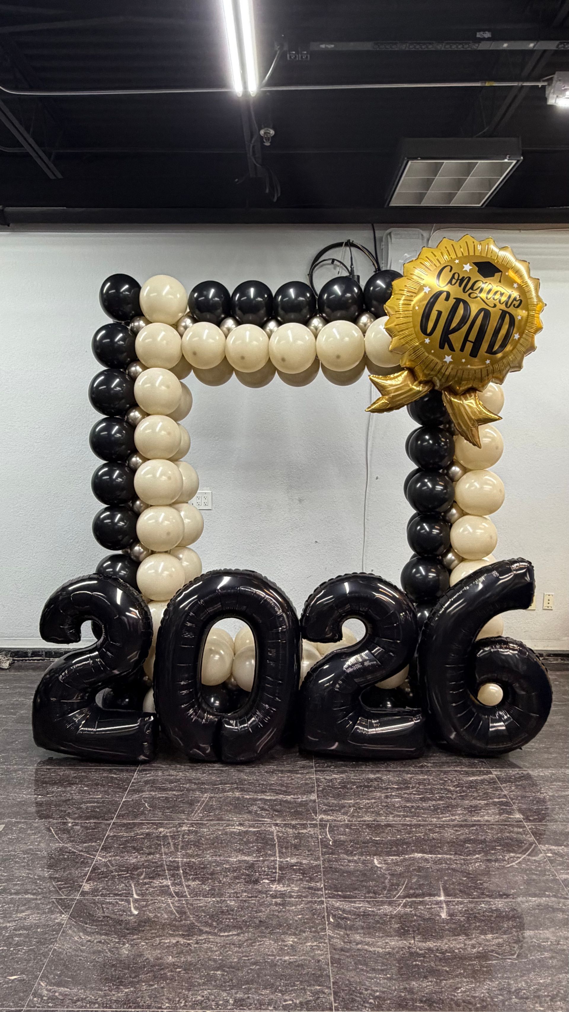 Black, cream, and gold balloon frame with “School” sign in a decorated indoor venue
