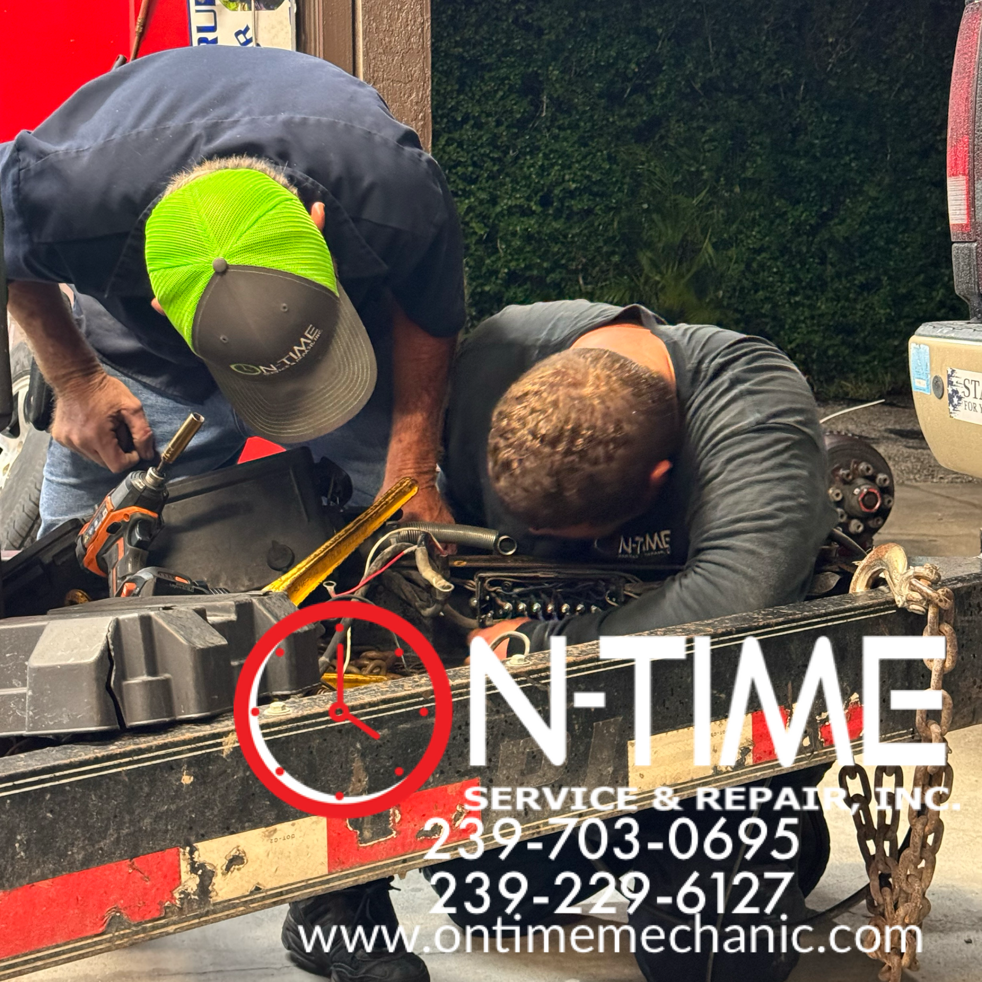 Two men are working on a truck with the website www.ontimemechanic.com in the corner