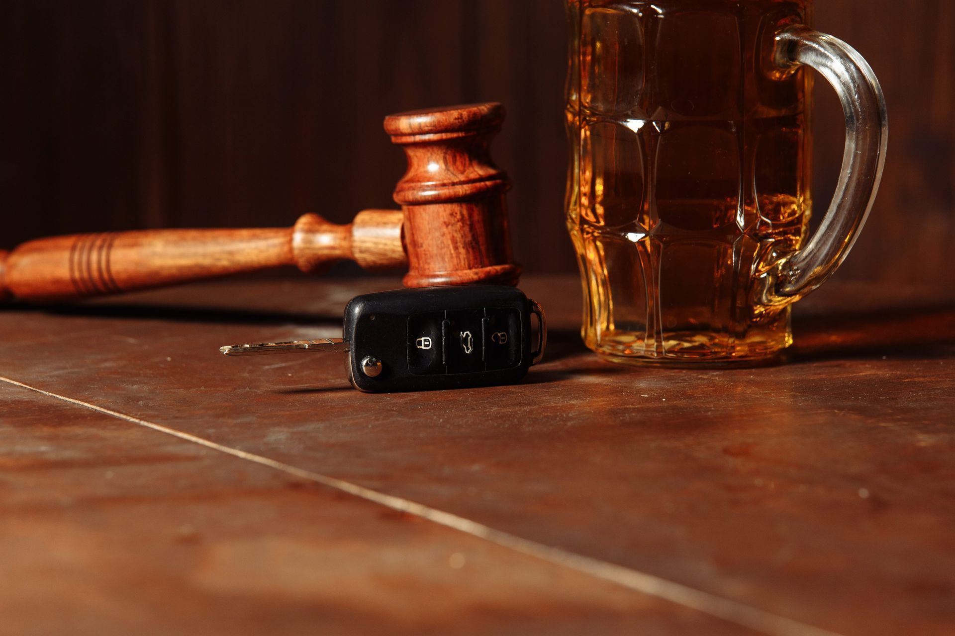 Gavel and judge’s hammer on a wooden table beside a glass mug of beer and a cigar box