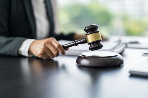 Judge’s gavel being struck on a sound block on a desk in a courtroom setting