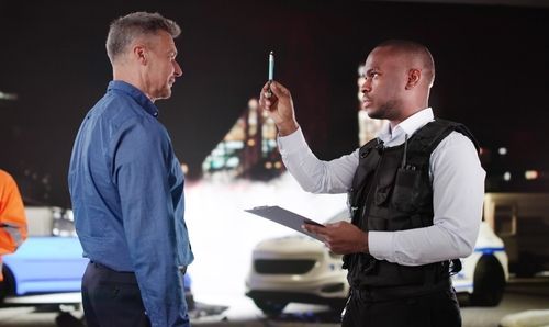 Traffic officer checking driver’s breath alcohol level with a breathalyzer at night roadside stop