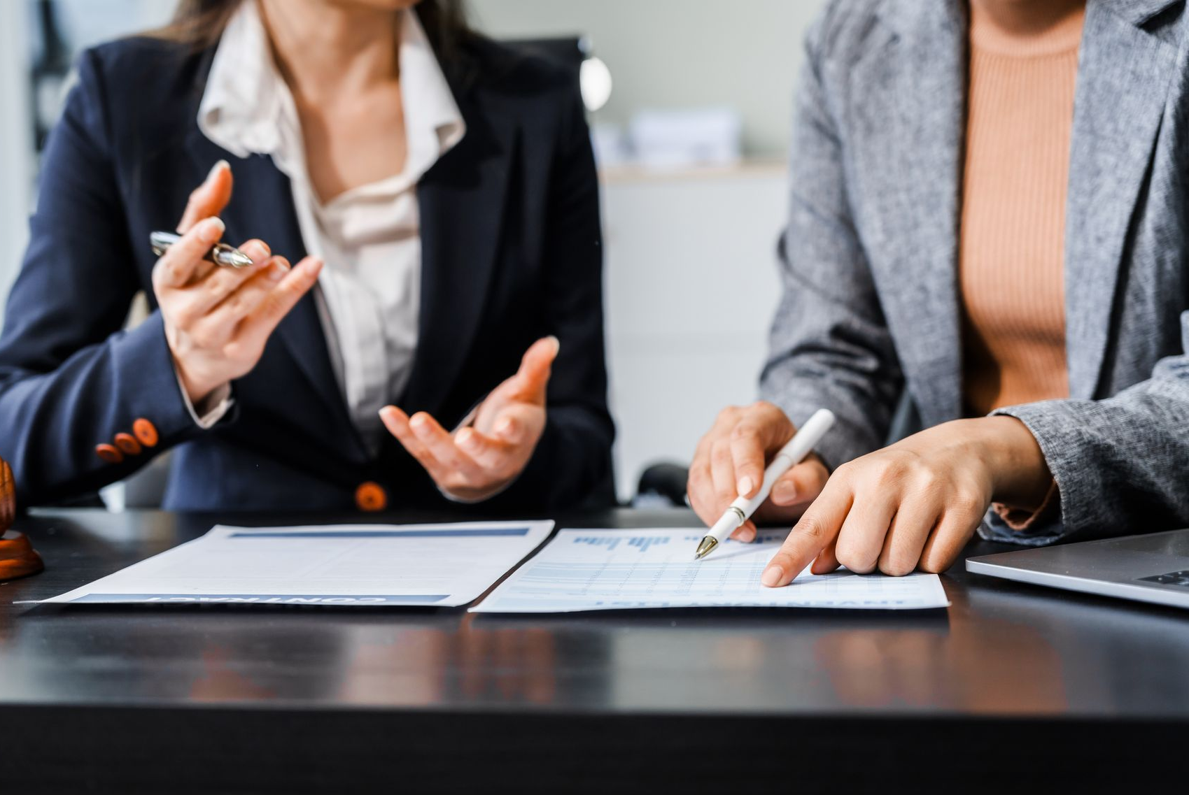 Two people in a bright office reviewing a document and smiling during a meeting Two people in a bright office reviewing a document and smiling during a meeting