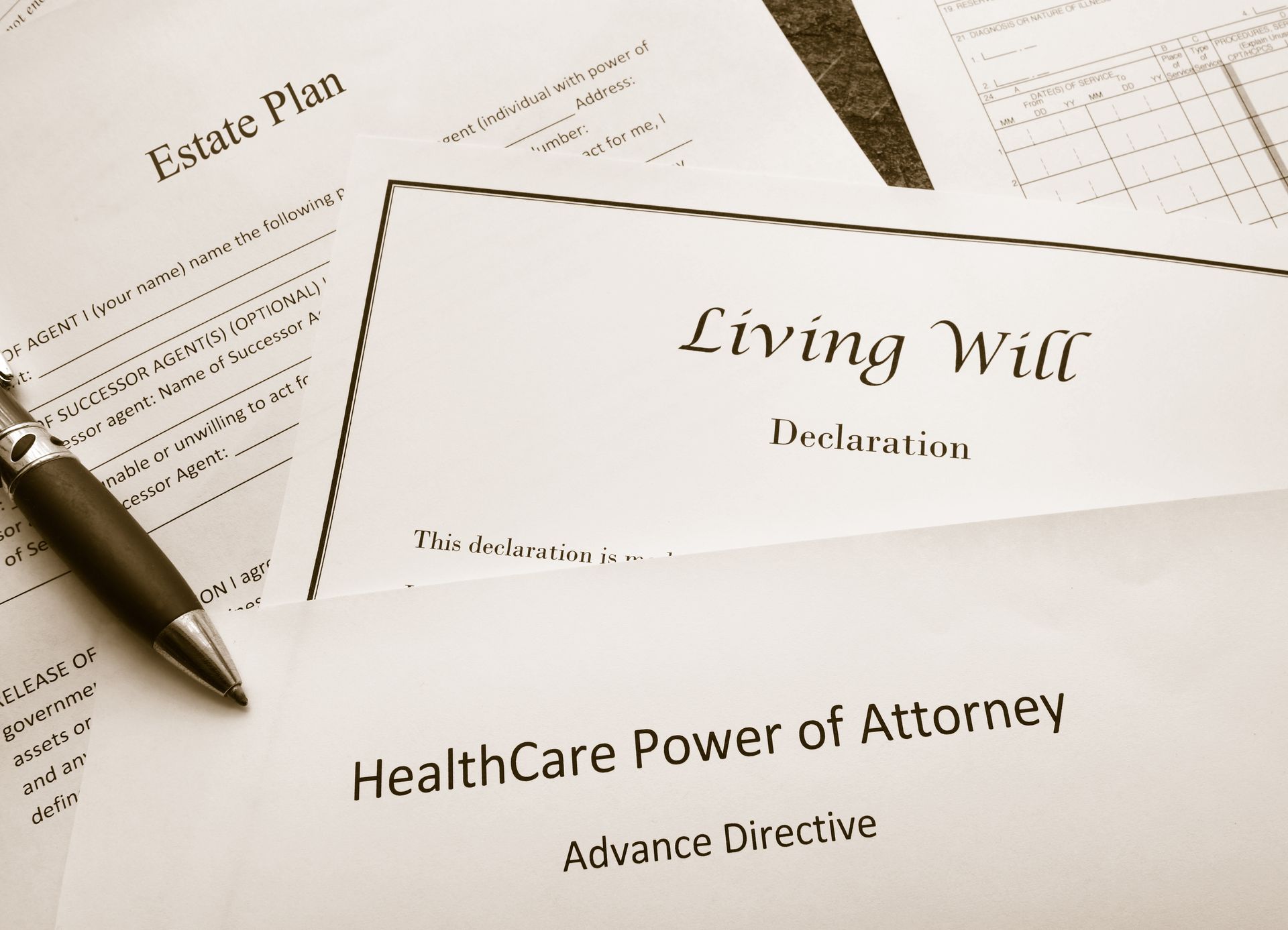 Advance directive documents on a desk, including a living will and healthcare power of attorney, with a pen.