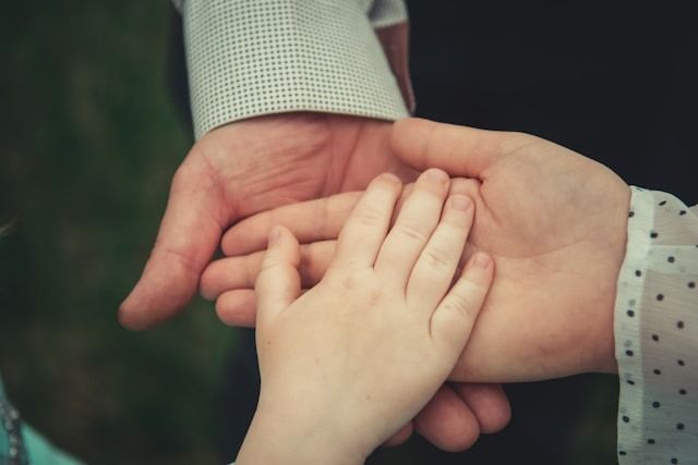 Adult and child hands gently holding together in a close-up shot