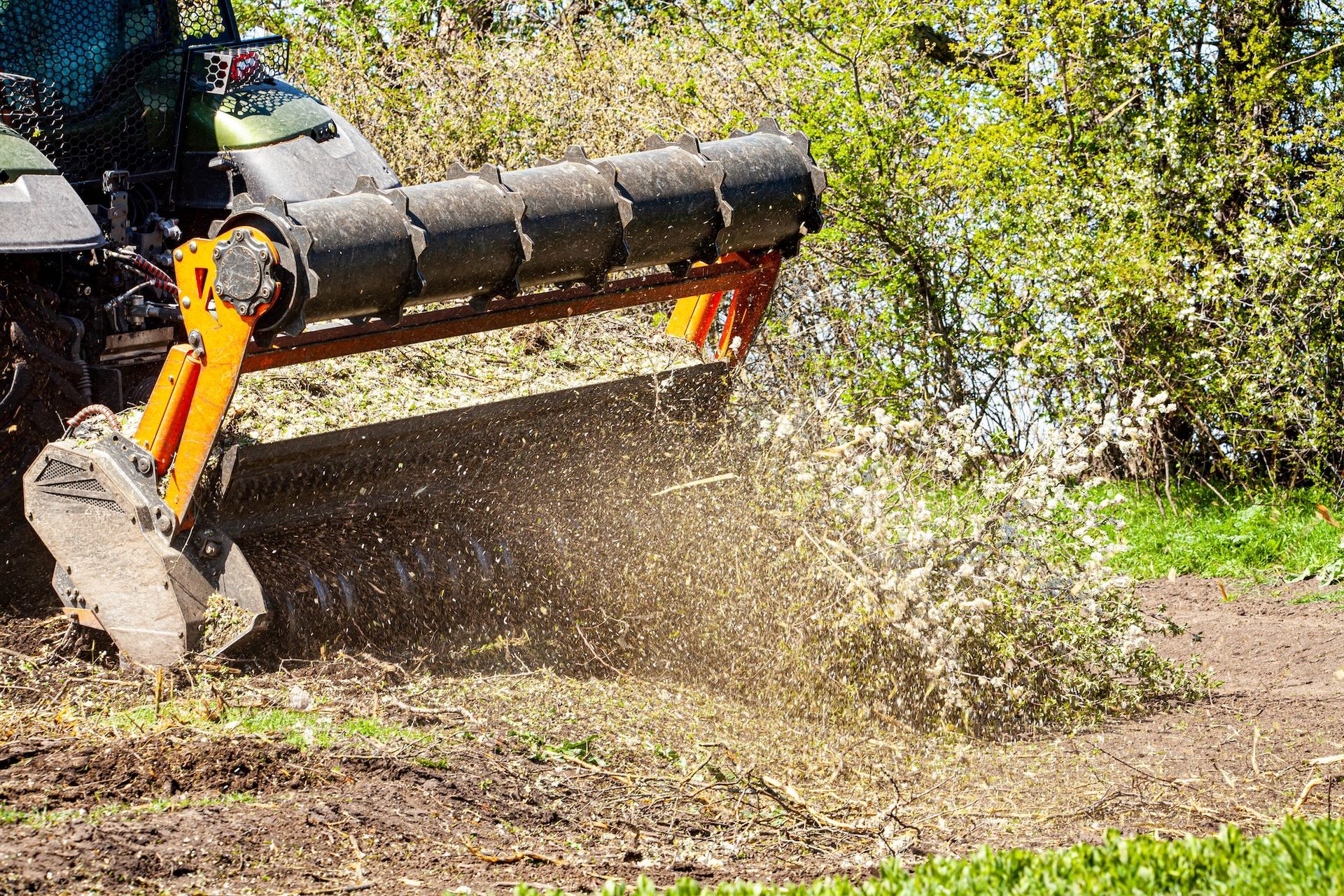 Excavator bucket clearing dirt and debris on a muddy construction site