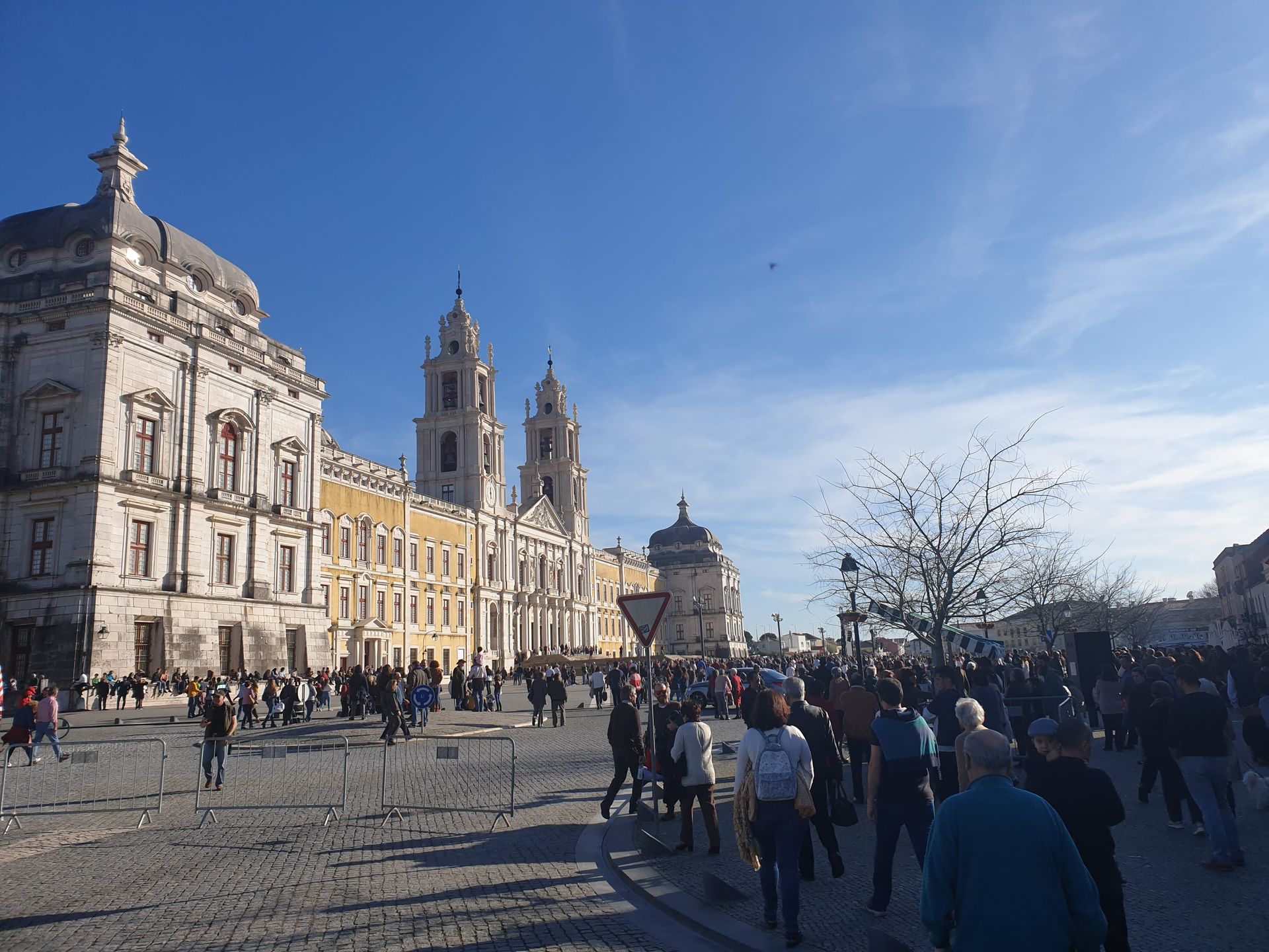 Crowded historic plaza with a grand cathedral and pale buildings under a bright blue sky