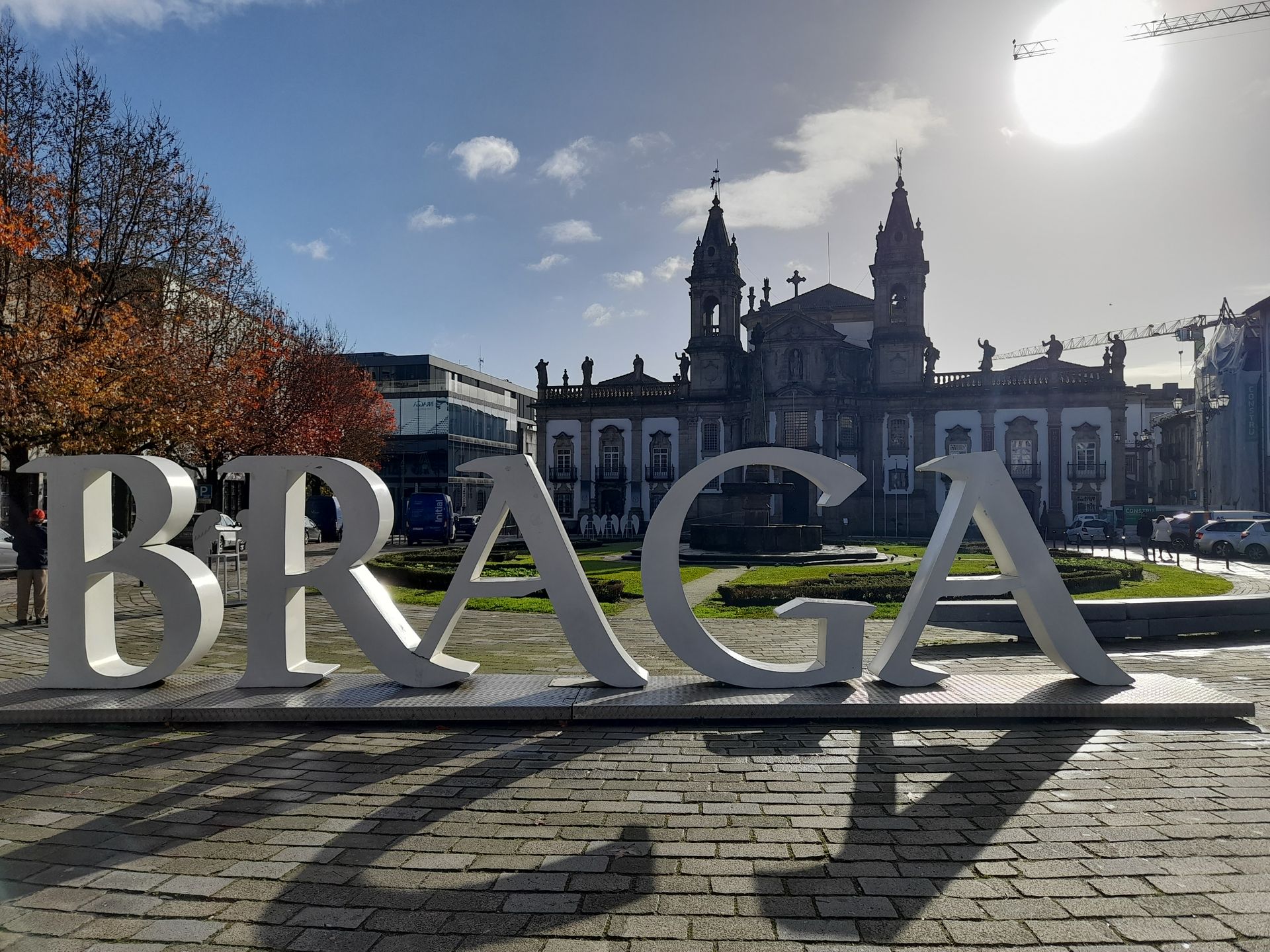 Large BRAGA sign in a sunny plaza with a historic cathedral in the background.