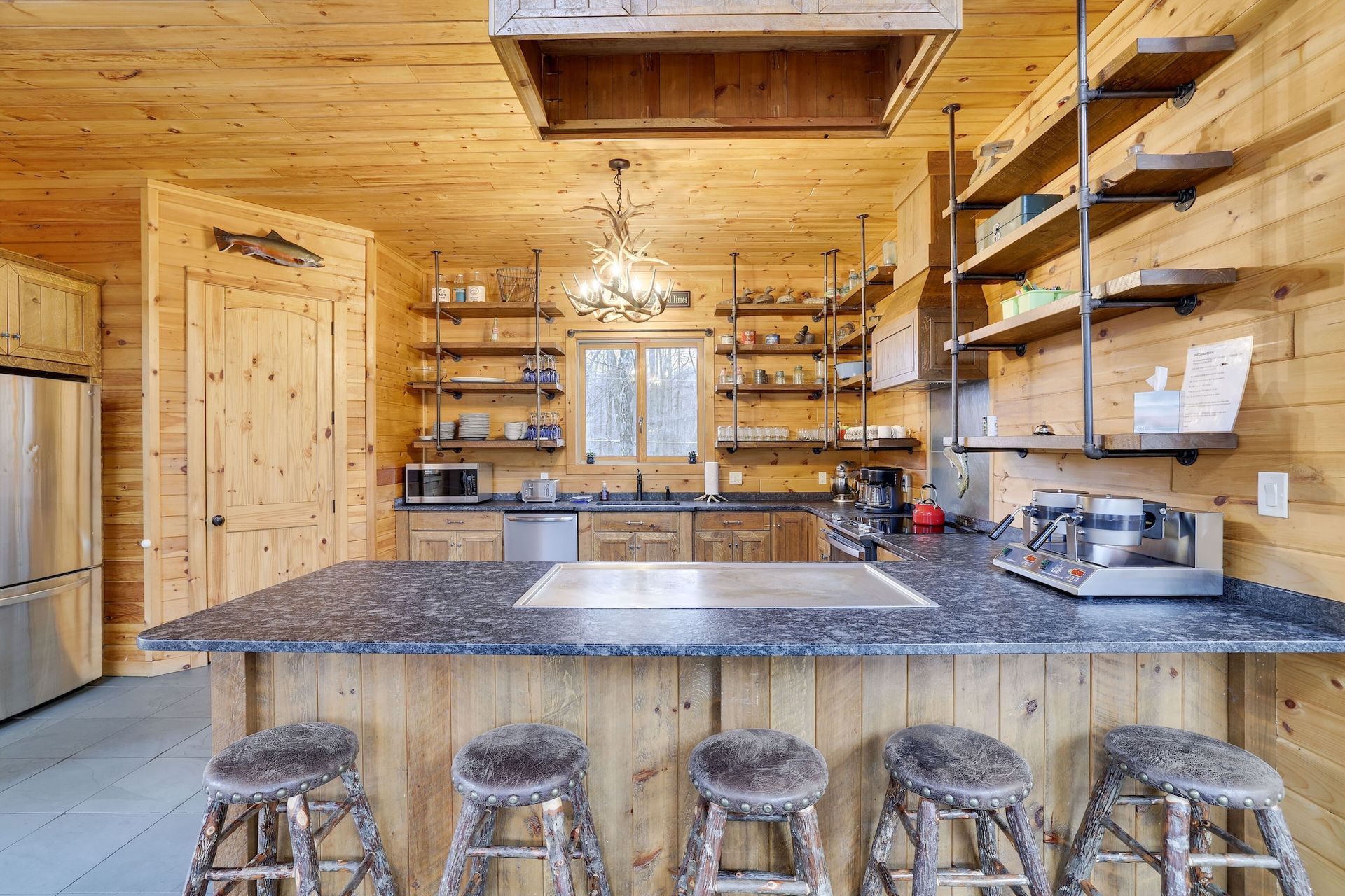 A kitchen in a log cabin with a large island and stools.
