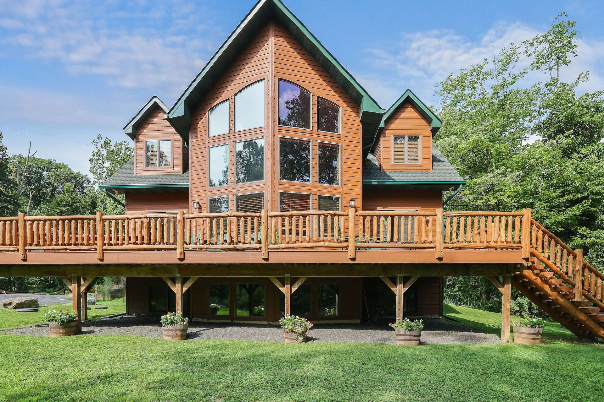 A large log cabin with a large deck and stairs