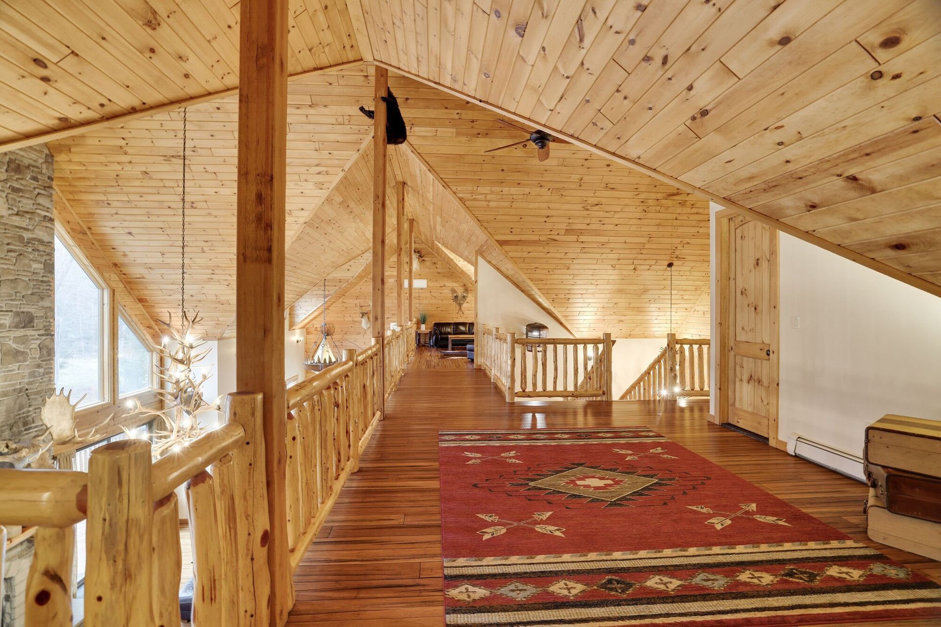 A wooden hallway with a rug on the floor and a wooden railing.