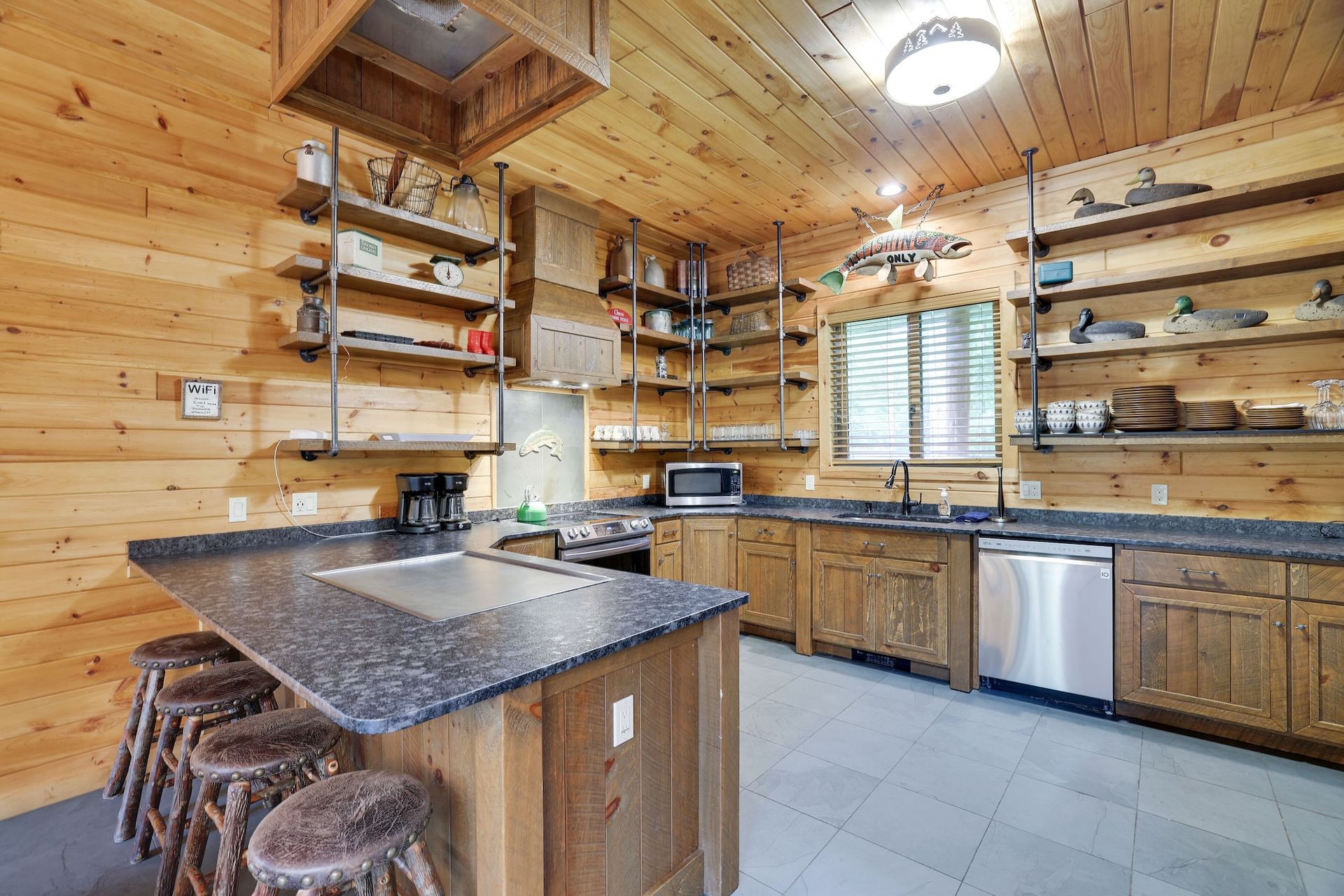 A kitchen in a log cabin with granite counter tops and stainless steel appliances.