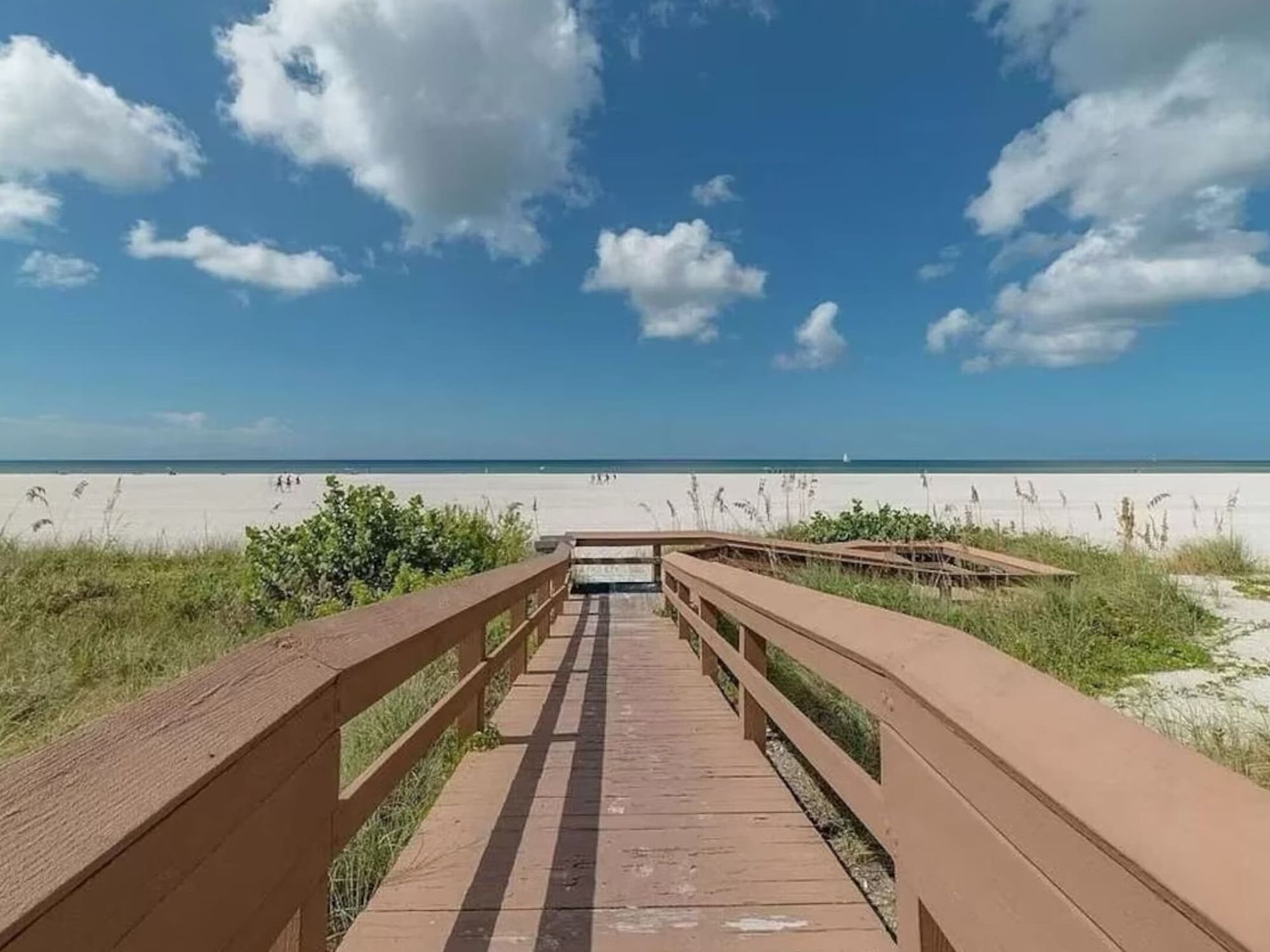 A wooden walkway leading to the beach on a sunny day