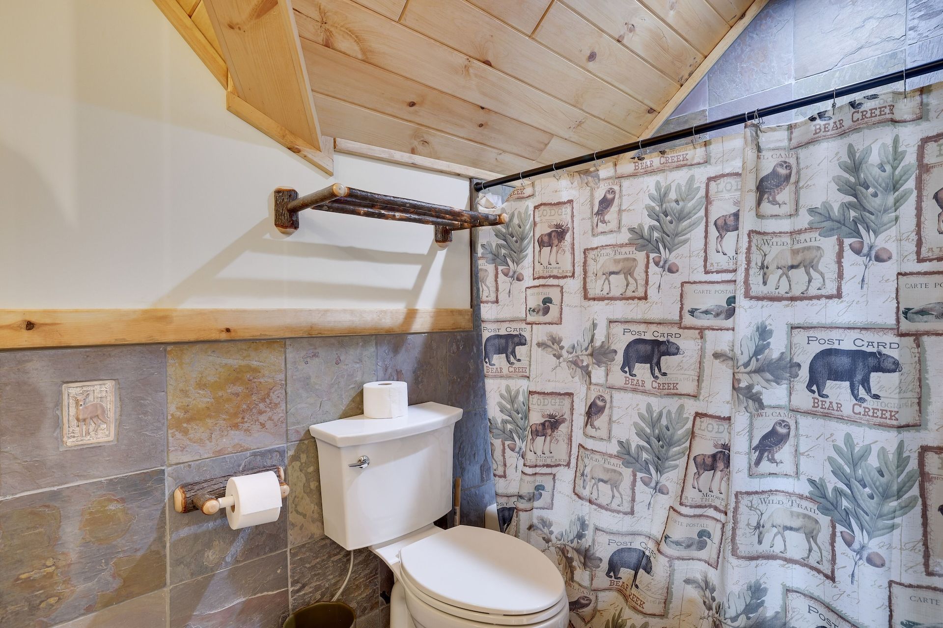 A bathroom with a toilet , shower curtain , and toilet paper.