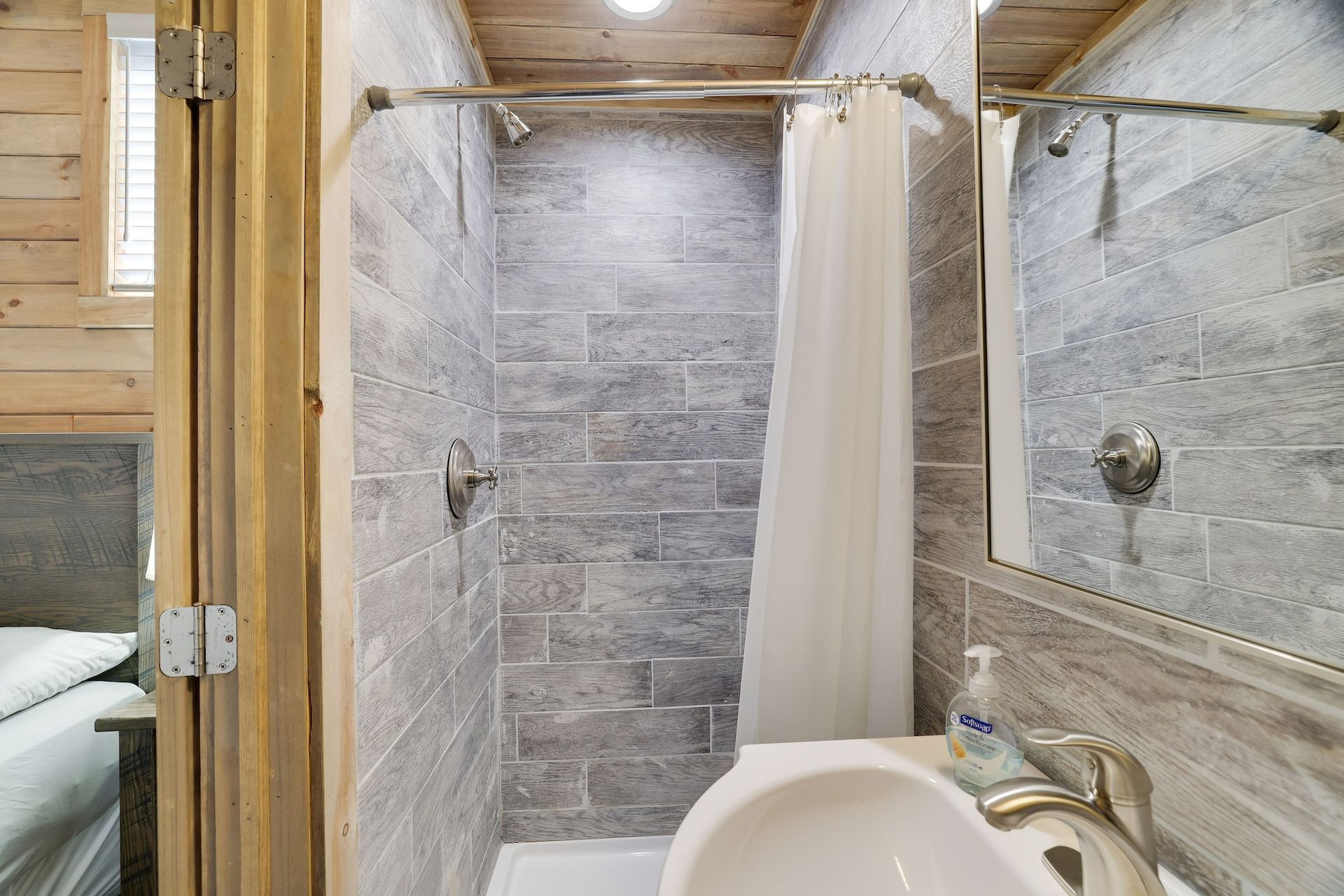 A bathroom with a sink , toilet , shower and mirror.