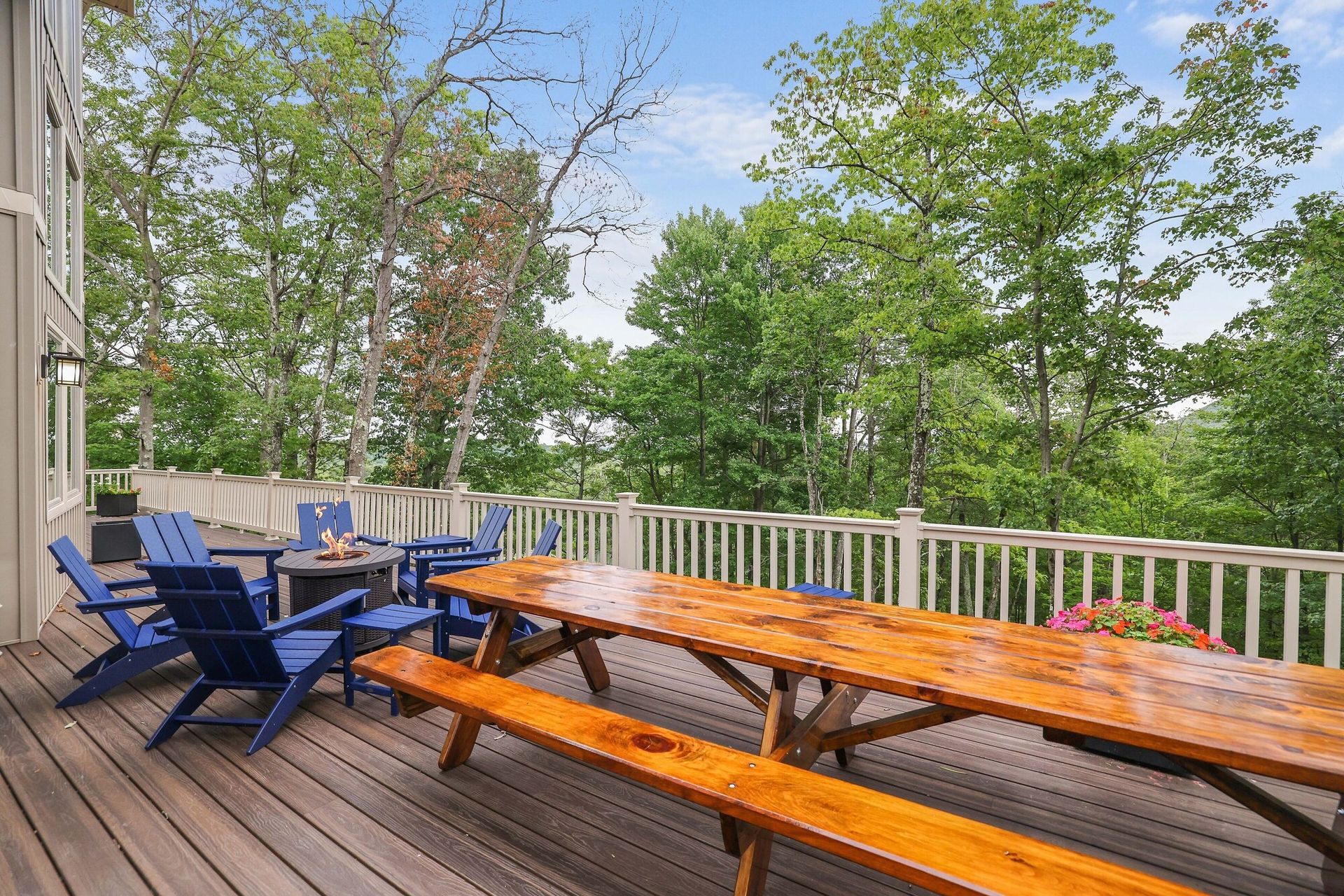 A large wooden deck with a picnic table and chairs.