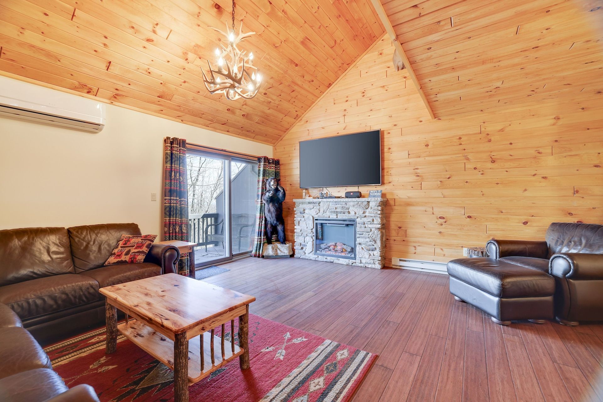 A living room with a couch , chair , coffee table , fireplace and television.