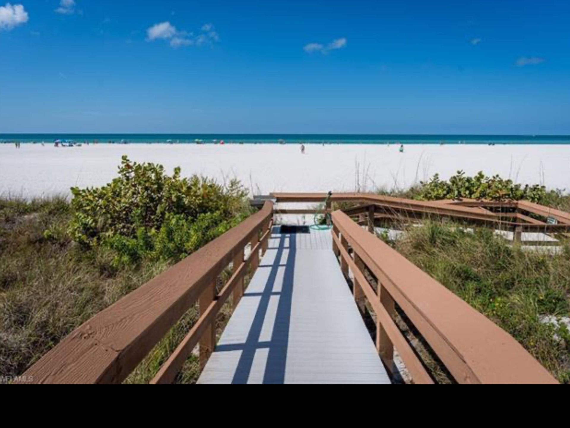 A wooden walkway leading to the beach on a sunny day